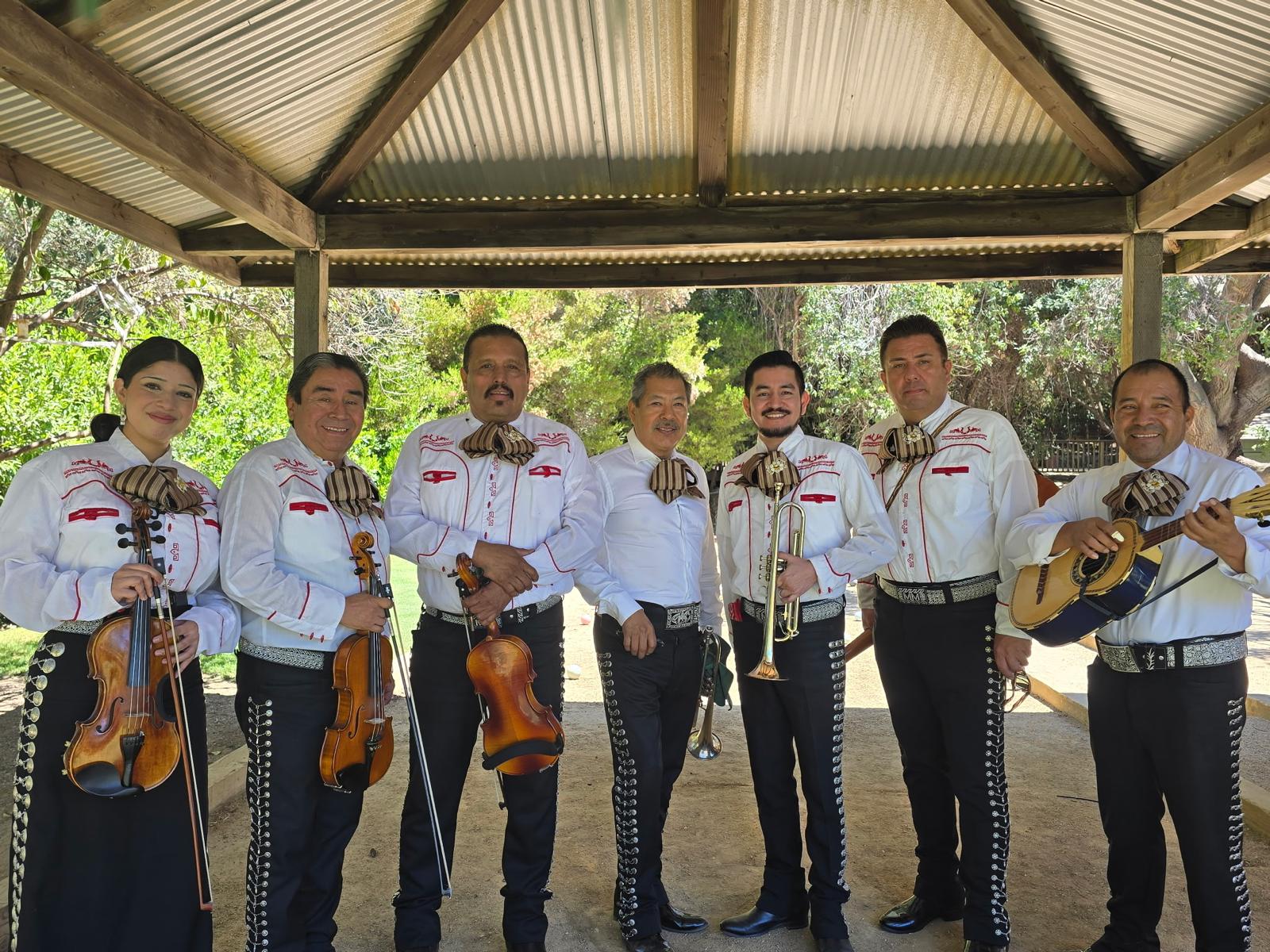 Mariachi musicians dressed in white beneath a pergola