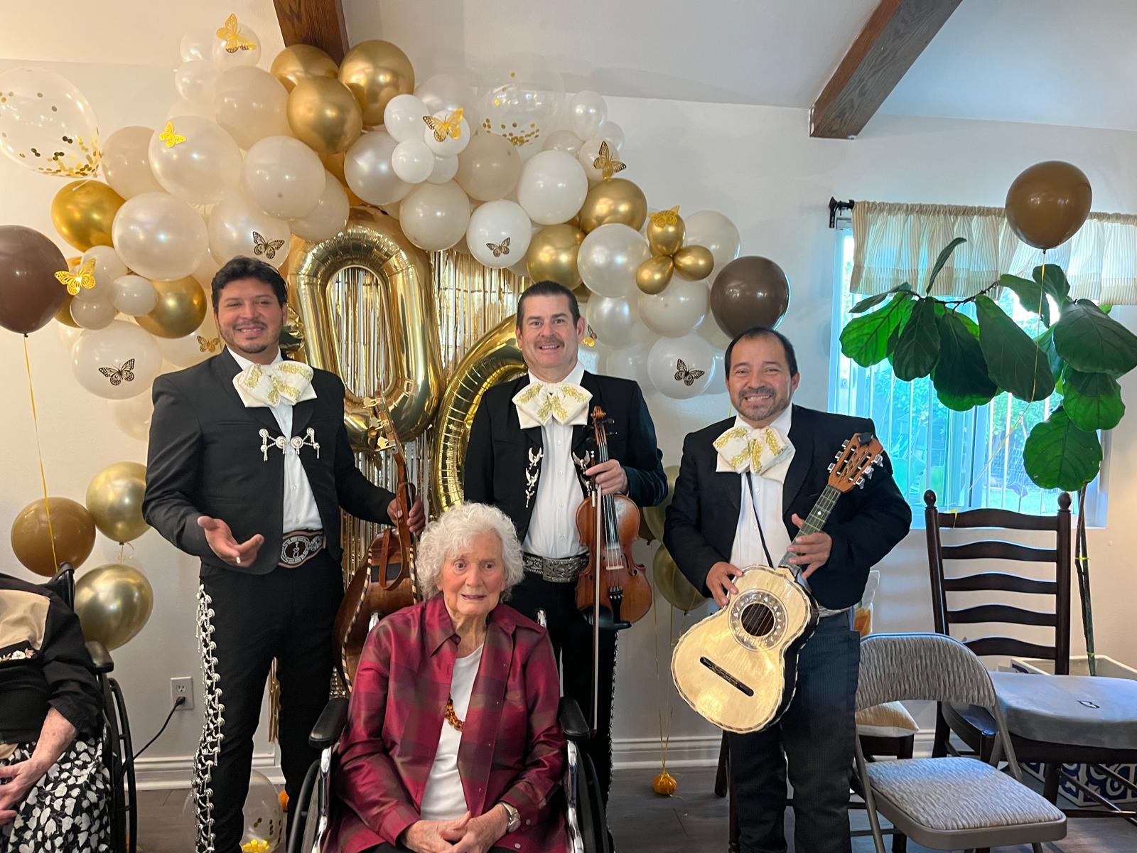 Three musicians with a woman on her 100th birthday